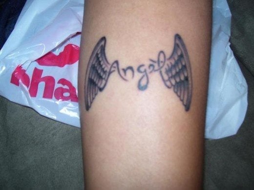 Tatuaje en el antebrazo de unas alas que custodian a la palabra ángel, un diseño original, con una tipografía que no nos gusta demasiado, pero para la que se ha escogido una bonita palabra y un remate más que aceptable de las alas