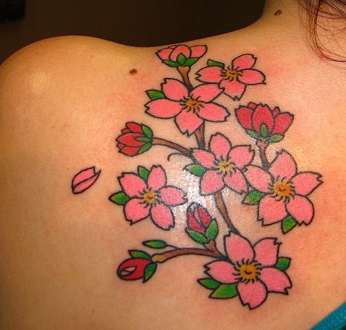 Conjunto floral tatuado sobre la espalda del que se caen algunos pétalos, unas flores sencillas con pocos sombreados y los colores justos para no resaltar demasiado y que no combinase, como podemos ver, un tatuaje sencillo