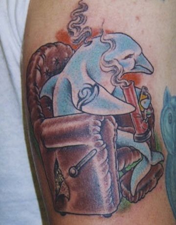 Alguien se imaginaría alguna vez un delfín sentado en un sillon, mientras fuma droga y que a la vez lleva tatuado un tribal en una de sus alas, pues se ve que a este hombre sí y por ello ha decidido tatuarlo sobre su piel, un tattoo surrealista por antonomasia