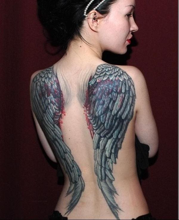Tatuaje de unas imponentes alas sobre la espalda, al que se le ha añadido el detalle de sangre roja, como si las alas estuvieran saliendo realmente de la espalda de la mujer, debemos añadir que el plumaje de las alas ha sido tatuado con gran destreza