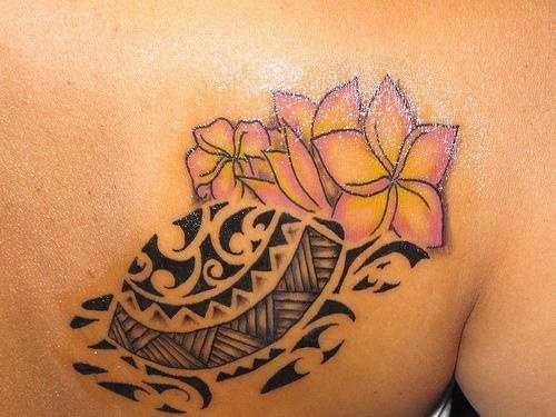 Tortuga de perfil de estilo maorí con varias flores rosadas al fondo acompañándola