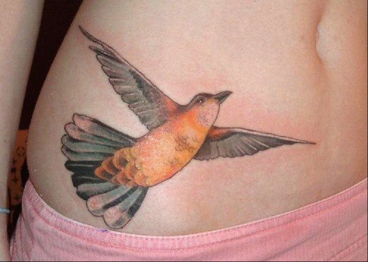 Tattoo de pájaro volando con unas alas muy bien definidas y un plumaje de un color anaranjado