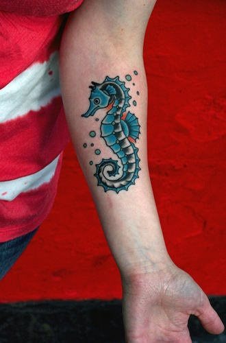 Tattoo en el antebrazo de un caballo de mar en tonos negros y azules, con alguna pizca de color rojo, al tatto le rodean unas bonitas pompas de agua del mismo color que el tatuaje, dotándolo de gran consonancia y dando como resultado un buen tatuaje