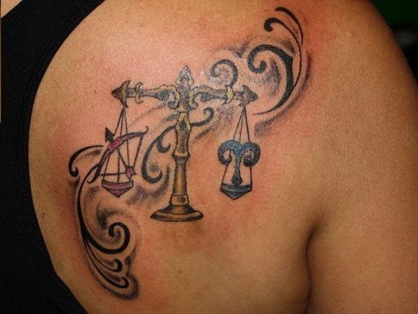 Tatuaje de una balanza en la que a cada lado se han realizado dos signos zodiacales diferentes, a la izquierda podemos observar el signo zodiacal de Sagitarios y a la derecha se aprecia el signo zodiacal de Aries y de fondo se han tatuado unas pequeñas cenefas que pegan muy bien con este tattoo