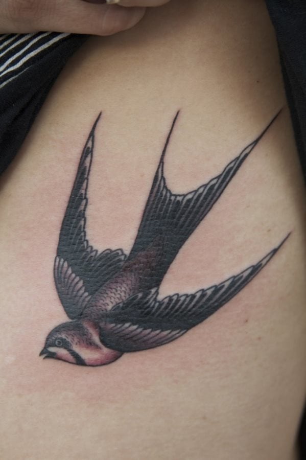 Tatuaje de una golondrina volando hacia abajo del que nos gustaría destacar las grandes líneas conseguidas para formar las alas y el remate final de las alas en pico, un bonito detalle para un tatuaje muy común en los últimos años