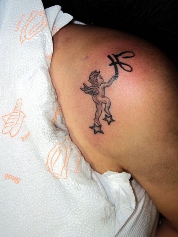 Tatuaje de un ángel infantil que parece estar posado sobre dos estrellas y en sus manos llevar la letra h, tal vez la inicial del nombre de su hijo o hija, una fantástica idea para todas aquellas madres que quieran llevar siempre con ella a su ser más querido