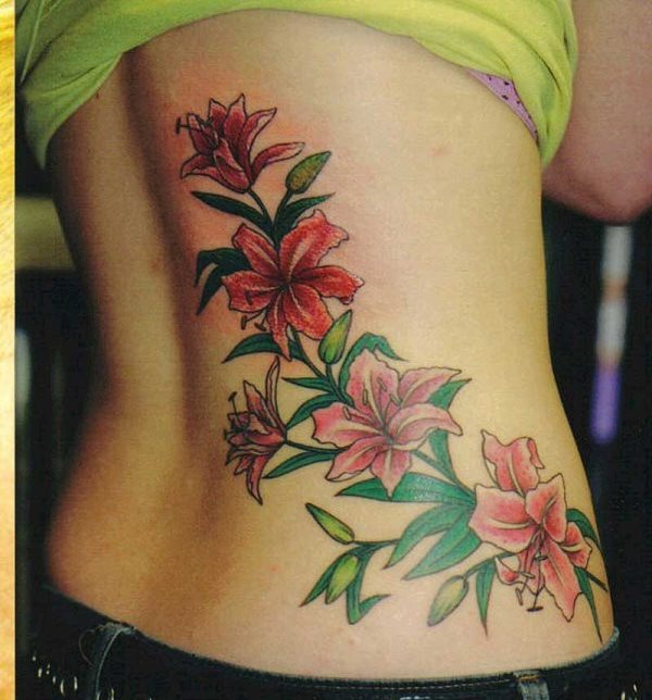 Tatuaje en la espalda de unas flores rojas, con unas preciosas hojas verdes y el capullo de alguna flores que todavía no han florecido, uno de los tattoos de flores más bonitos que mostramos, en el que resalta la originalidad de las hojas, diferentes a las que habíamos visto hasta ahora y las flores que aún no han florecido