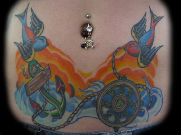 Bonita composición de tatuaje en el abdomen formado por dos pájaros que agarran unas cuerdas y un ancla, en este tattoo los colores anaranjados y azulados le dan un contraste muy acertado al tattoo