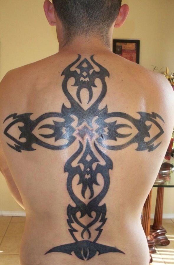 Tatuaje de una cruz tribal de gran tamaño que recorre toda la espalda y para el que se han utilizado gruesos trazos y se han rellenado al completo de color negro