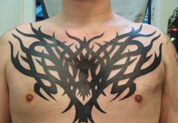 Gran tatuaje de un enorme tribal sobre el pecho que parece un árbol y que llama bastante la atención, sobre todo por su enorme tamaño para la zona en la que se ha plasmado y que será difícil de esonder a menos que llevemos una camiseta cerrada de cuello redondo