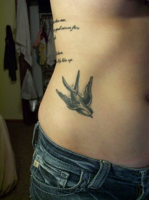 Golondrina hecha de tinta negra tatuada en un lado del abdomen