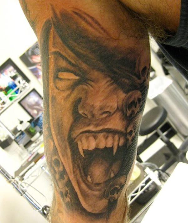 Tatuaje que cubre todo el bíceps y el tríceps de un vampiro en posición de pocos amigos y cuyo tatuaje ha sido completado con unas pequeñas calaveras, también a color negro, situadas en el interior del brazo