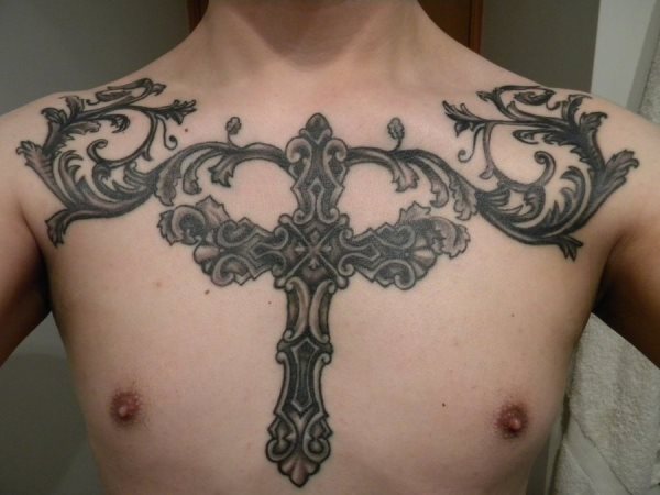 Elaborada y recargada cruz rodeada de ramas tatuada sobre el pecho de este chico