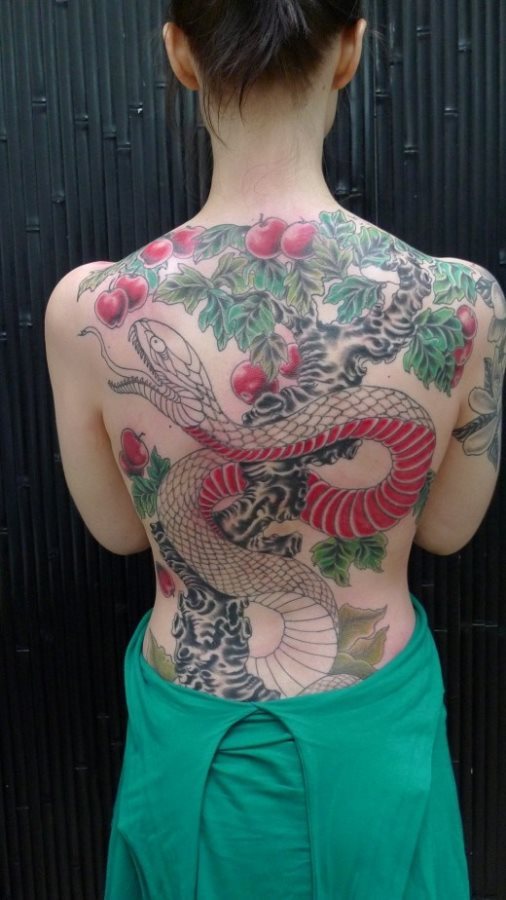 Tatuaje de un árbol lleno de manzanas rojas y rodeado por una serpiente que parece estar cogiendo una manzana y que nos recuerda al paraíso que Dios les regaló a Adan y Eva