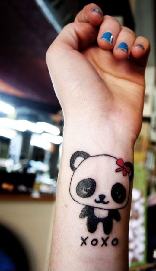 Tatuaje en la muñeca de un divertido oso panda con un lacito rojo, un tatuaje peculiar y una zona también original para hacer este tipo de dibujos, ya que hasta ahora, acostumbrábamos a ver palabras o frases en la muñeca y esta vez se ha decidido por este sencillo tattoo de oso