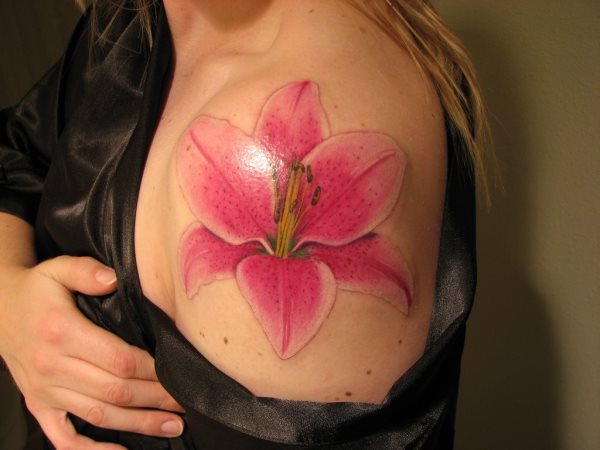 Tatuaje en el hombro de una flor rosa de grandes pétalos que le dan un aire súper femenino a esta chica y muy sensual, un gran acierto de tatuaje y una zona perfecta para llevarlo a cabo, nos encanta este tatuaje