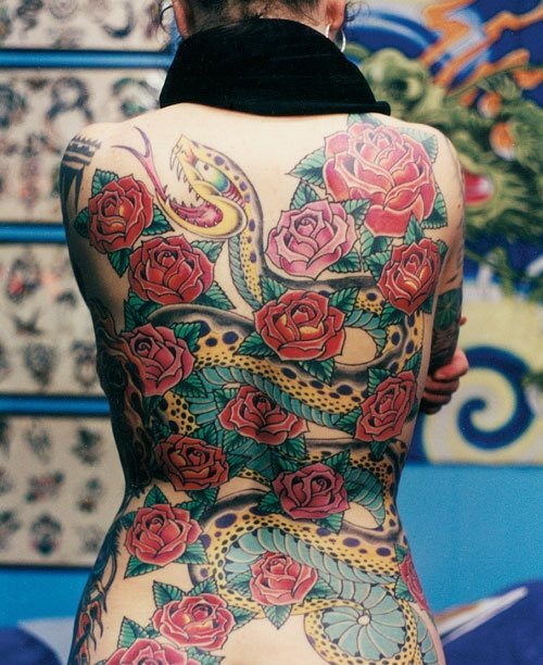 Tatuaje de una enorme serpiente atacado que ocupa toda la espalda y que ha alcanzado la perfección de tatuaje gracias a las enormes rosas rojas con unas hojas verdes súper bonitas