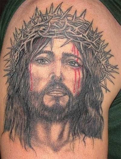 Tatuaje de Jesucristo para el que se ha realizado una perfecta combinación del rostro de Jesús a color negro y dejando sólo algunos detalles en rojo, como es la sangre que le chorrea por la cara, magnífica la delicadeza con la que se ha tatuado el color rojo en la piel