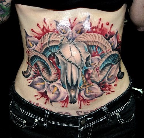 Tatuaje de gran tamaño en el abdomen constituido por una calavera y unas flores blancas preciosas que dan un buen aspecto a este tatuaje, al igual que los brotes de sangre que bordean el tattoo