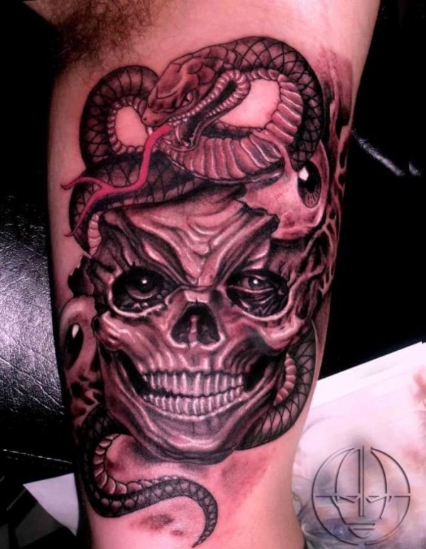 Tatuaje de una serpiente que rdeoa una calavera de varios ojos de la que aún no se ha desprendido toda la piel, dando un aspecto más sangriento si cabe y sin duda un resultado buenísimo, en el que las pequeñas betas en color blanco dan un gran realismo a este tatuaje