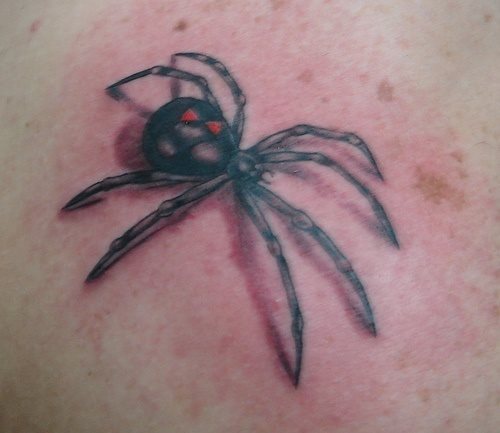 Tatuaje de una araña negra con dos triángulos rojos, de la que nos gustaría destacar lo bien que ha quedado la cabeza de la araña y como se pueden apreciar toods los pequeños detalles de este insecto, un buen trabajo