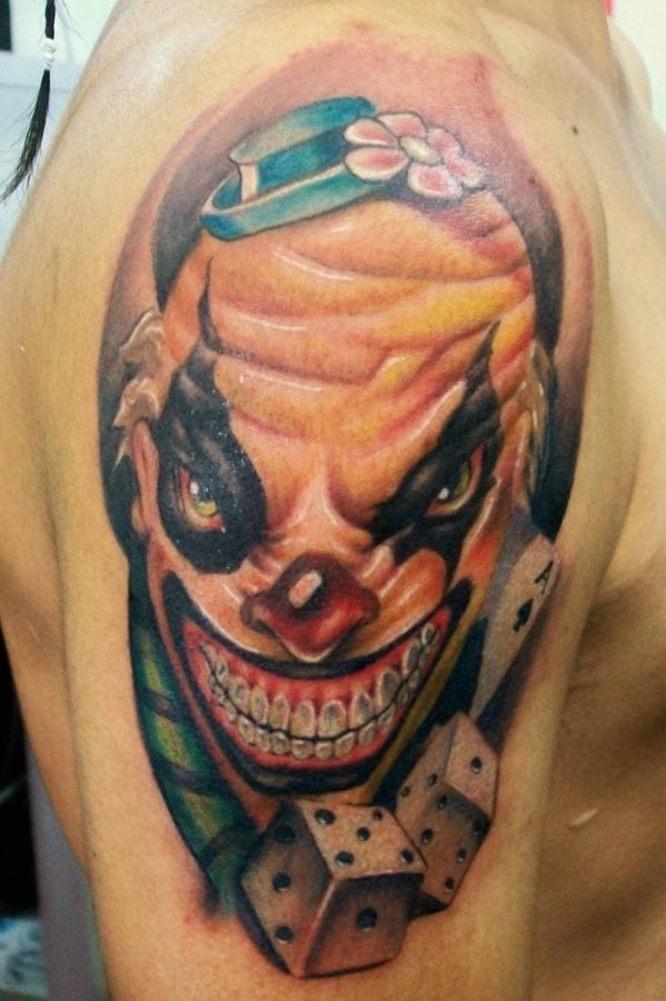 Colorido diseño el de este tatuaje de payaso calvo con un pequeño sombrero y flor que ocupa todo el bíceps del tatuado, este tatuaje nos gusta por lo realista que han quedado las arrugas del payaso al cominar a la perfección el color naranja, con los tonos rojos y rosas que le dan un realismo impresionante