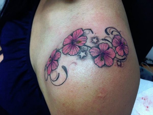 Tatuaje floral compueto por cuatro flores de color rosa con pétalos sombreados y unidas cada una por una cenefa de color negro con trazos finos y acabados más gruesos, además se han tatuado unas pequeñas y disimuladas estrellas alrededor