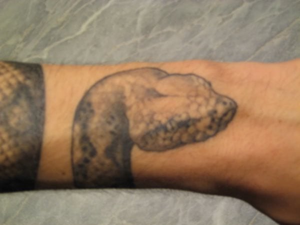 Tatuaje de una serpiente que va rodenado todo el antebrazo y acaba la cabeza en la muñeca