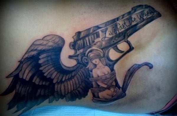 TAtuaje de una pistola alada, en la que podemos ver como en el cañón aparece la frasse 