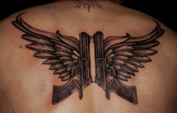 Tatuaje de dos pistolas mirando hacia el cielo que se ha realizado sobre la espalda y a la que se le han incorporado dos grandes alas, estamos ante un original tatuaje, en el que vemos una gran elaboración en las alas, pero a la pistola le harían falta tatuar algunos detalles para que quedaran tan bien como han quedado las alas