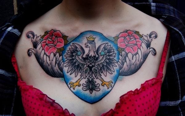 Tatuaje de un águila envuelto en una pompa azul y en los laterales unas alas negras sobre las que se han tatuado dos rosas rojas, un tatuaje que hasta ahora sólo estábamos viendo en hombres, pero que a esta mujer le ha quedado genial y resaltará aún más su pecho
