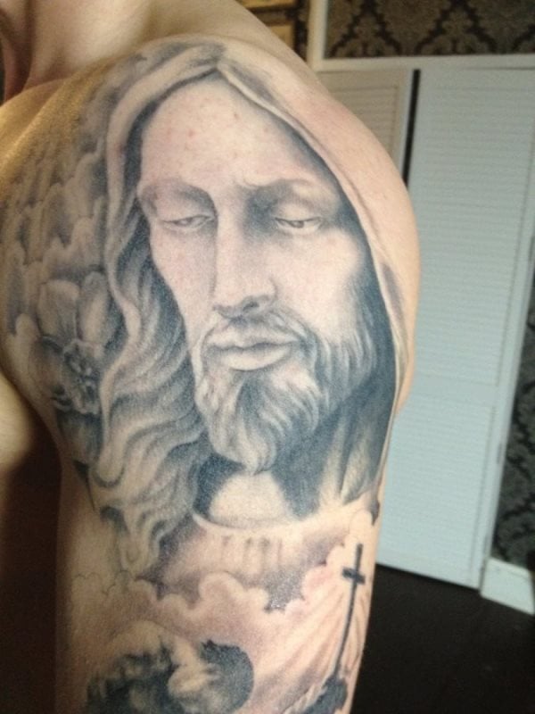 Espectacular tatuaje del semblante de Jesucristo, que refleja un gran misterio en su mirada y que ha sido completado con un maravilloso fondo de sombreados emulando al cielo, un buen trabajo sin duda alguna