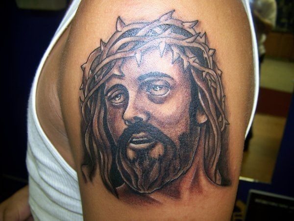 Tatuaje en el brazo del rostro de Jesucristo mirando hacia arriba y con una corona de espinas, tal y como se expresa en la Bilbia que fueron sus últimos momentos, antes de morir por nosotros en la cruz
