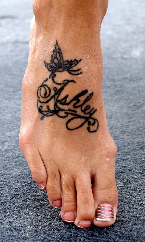 Un nombre propio con una mariposa en la cima del tatauje ocupan el empeine de este pie
