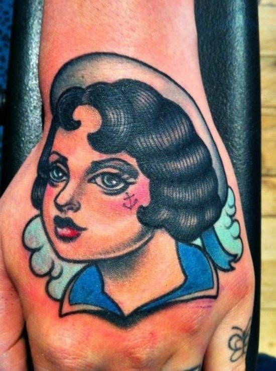 Mujer marinera al estilo americano, en cuya cara de la mujer tatuada se ha tatuado un pequeño ancla