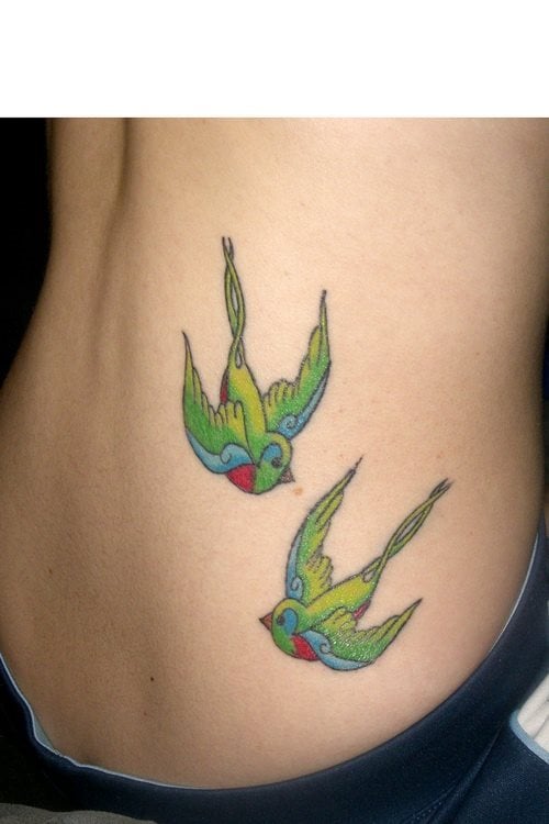 Tatuaje de dos golondrinas verdes en pleno vuelo, la zona elegida para este tatuaje es la cintura y la verdad es que se ha conseguido un resultado final muy bueno, para nuestro gusto gracias a los colores escogidos