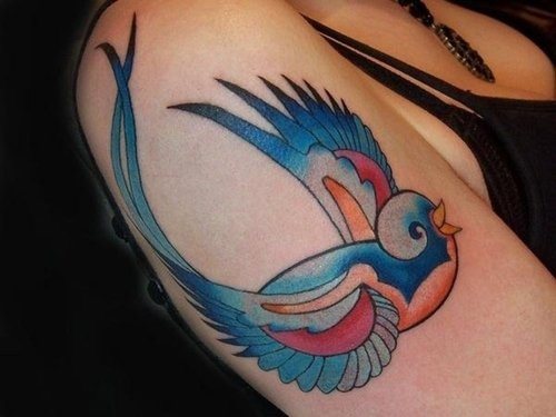 Tatuaje de una colorida golondrina del que nos gustaría resaltar el gran resultado conseguido en las alas, sobre todo por los remates en punta a color negro y por la cola que parece salir de una de las alas