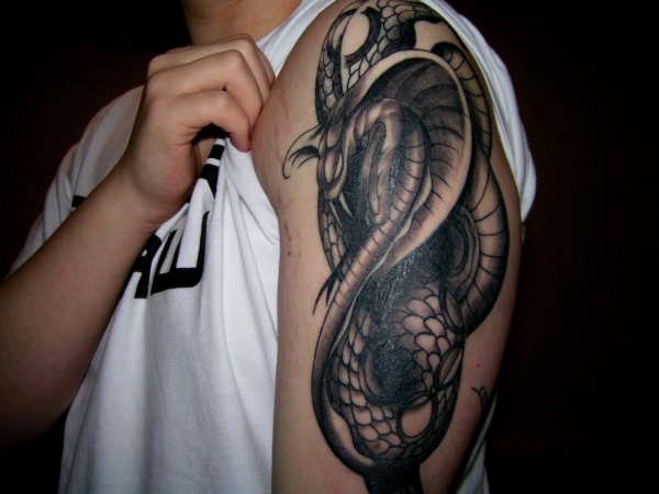 Oscuro tatuaje de una cobra sobre el brazo de un hombre