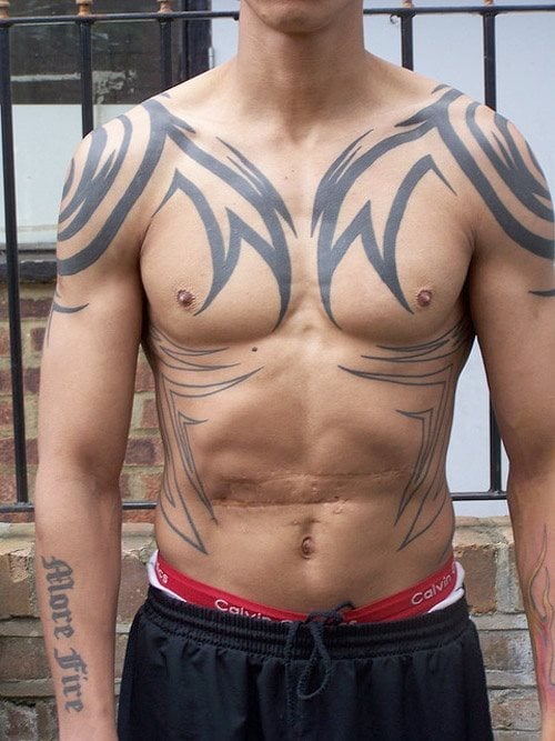 Tatuaje tribal sobre el pecho de un hombre de pezones pequeños, que como vemos el tatauje se está extendiendo también por el abdomen, aunque todavía no ha terminado de rellenar, aunque estamos seguros que cuando lo haga, le quedará un dibujo brillante sobre su cuerpo