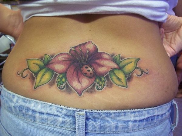 Tatuaje en la parte cervical de la espalda, de una flor roja oscura con hojas verdes y sobre la que está posada una simpática mariposa, sin duda el detalle de la pequeña mariposa le da un aire de originalidad que nos gusta bastante