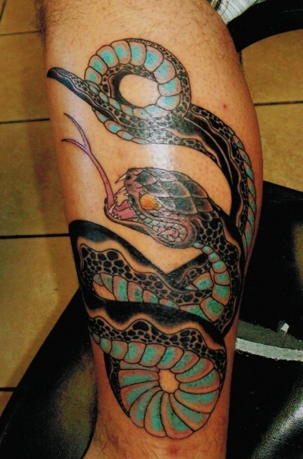 Tatuaje de serpiente que cubre gran parte de la pierna y del que nos gusta especialmente el color turquesa utilizado para colorear gran parte de las escamas de la serpiente, creemos que este color es el que tiene el protagonismo en el tattoo y que a la vez le otorga una gran originalidad