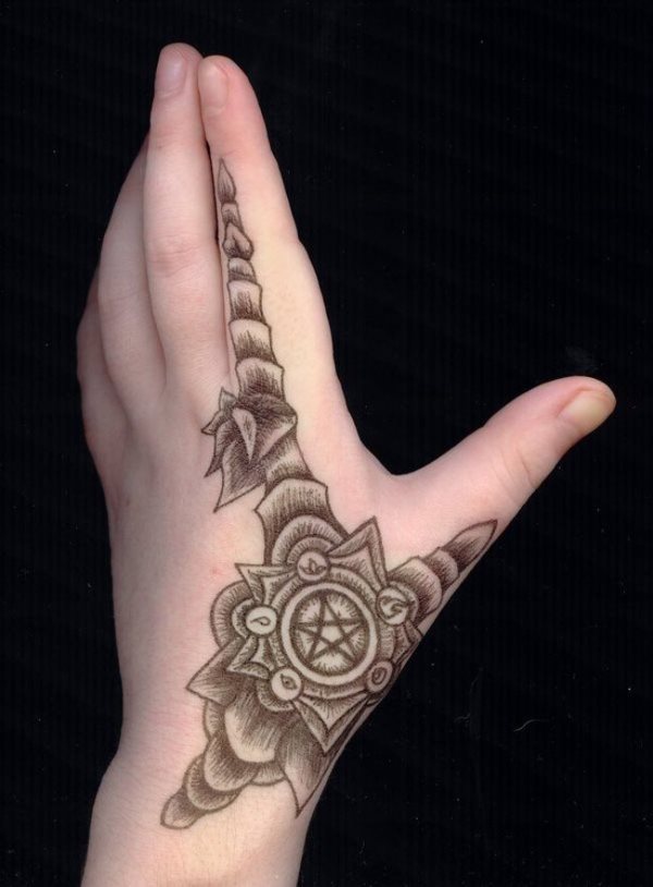 Tatuaje de flor sobre la mano, en la que se ha tatuado una estrella en el centro y va recorriendo todo el dedo con lo que parece una vela de hueso y que es muy original al extenderse tanto el dedo índice como por el pulgar