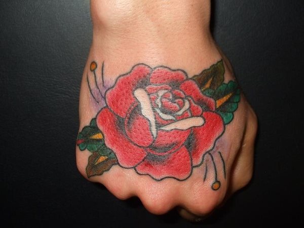 Rosa roja con decoraciones de otros colores como son las hojas en color verde y amarillo, a la vez que el difuminado morado hacen de éste un buen tatuaje en el puño de la mano