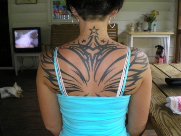 Espectacular tatuaje con motivos tribales y estrellas que ocupa toda la espalda de esta chica