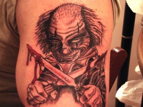 Sangriento diseño de un payaso con dos cuchllos en la mano ensangrentados, esperemos que no te dé demasiado miedo el tatuaje, aunque creo que puede ser la idea que intenta infundir el propio tatuado, con este payaso medio calvo medio rapado