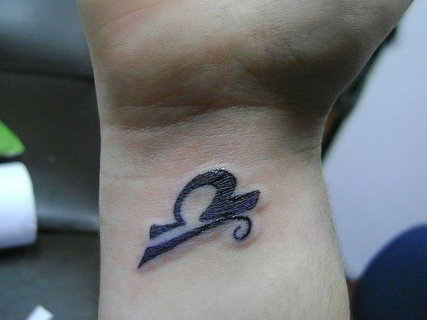 Tatuaje en la muñeca del signo zodiacal Libra, un tattoo pequeño y coqueto a color negro, que simboliza el equilibrio y la armonía y su símbolo representa la balanza, perteneciendo junto a Géminis y Acuario al elemento aire