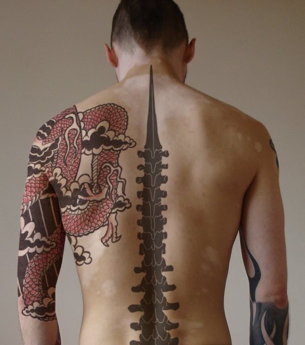 Tatuaje que parece estar elaborado con algún programa de diseño digital de las fotografías, del que destacamos el principio de flecha de la columna vertebral y el imponente dragón que se ha dibujado sobre el brazo y que llega hasta la espalda, con un perfecto trazado de las escamas y unos colores elegidos, que llevados a la realidad quedarían muy bien