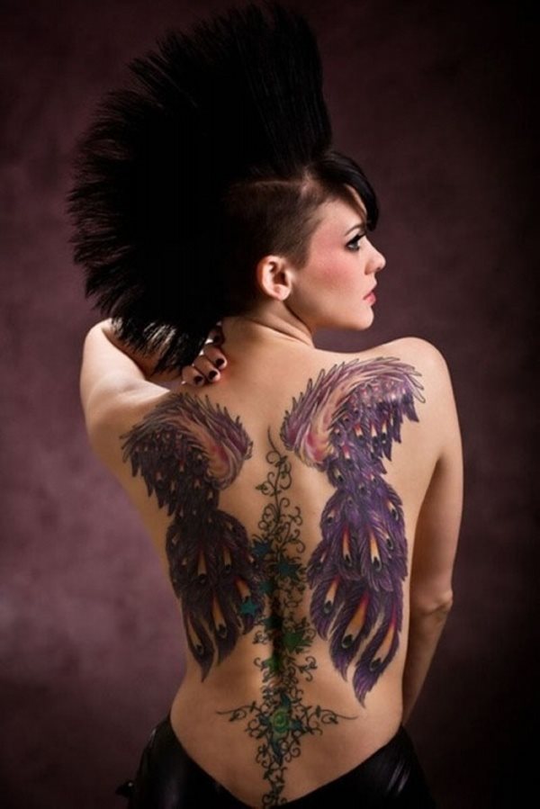 Tatuaje de unas enormes alas moradas, con unos colores y trazados espectaculares con aire de plumaje de pabo real y en el centro de las alas, unas cenefas de trazos finos que recorren toda la columna vertebral