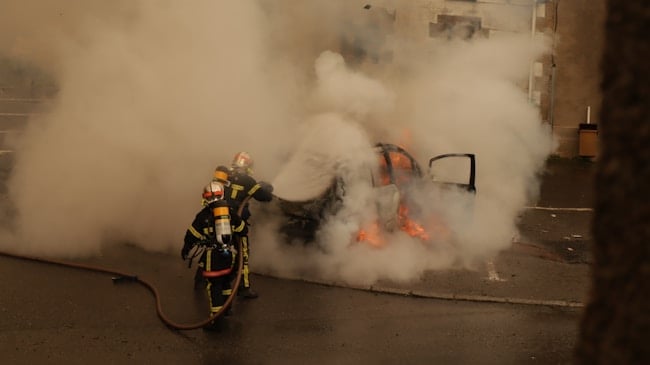 Pompiers évacuant le feu d'une voiture accidentée
